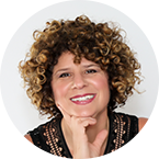 Denise Pane portrait - with her curly brown hair, black sleeveless blouse, hands on her chin and a smile