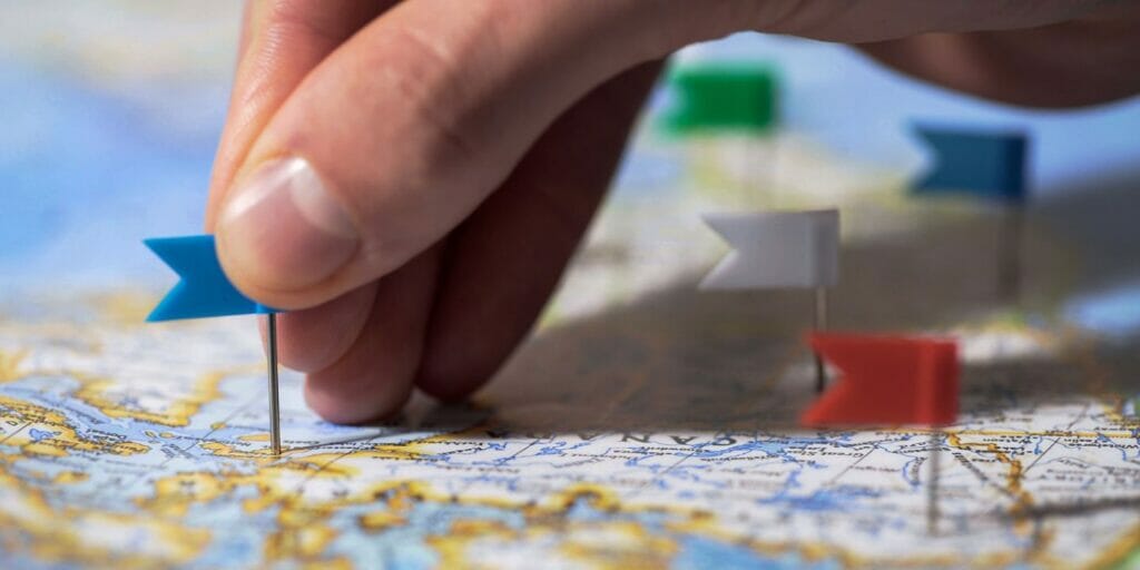 a close up of a person's hand pointing to a pin on a map of canada