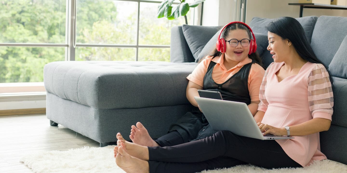 A lady and daughter with disability happily listening to a laptop program