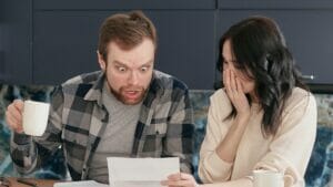 A couple looking at a bill with a shocked look in their faces