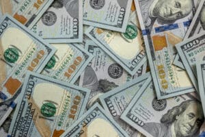 A scattered pile of U.S. one hundred dollar bills covering the background